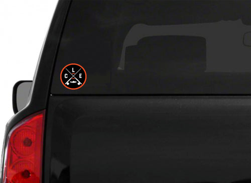 An orange circle around white CLE crossed fishing rods sticker on the back of a black truck.
