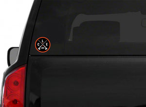 An orange circle around white CLE crossed fishing rods sticker on the back of a black truck.